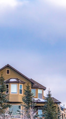 Clear Vertical Exterior of an elegant house against blue sky with puffy clouds in winter