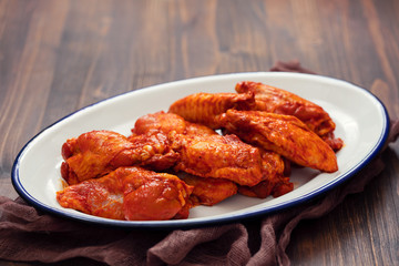 marinated chicken on white dish on brown wooden background