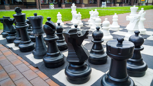 Closeup image of black and white big chess figures for playing in park.