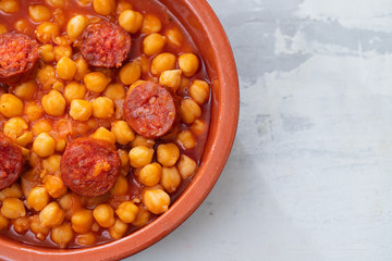 chick pea with smoked sausage chorizo  in small brown ceramic dish