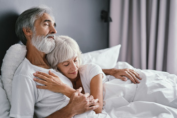 Obraz premium Happiness and tender. Senior family. Husbang hugging his wife in bed.