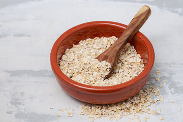 dry oats with spoon in ceramic bowl
