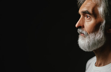 Close up studio portrait of handsome senior man with gray beard.