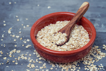 Obraz na płótnie Canvas dry oats with spoon in ceramic bowl