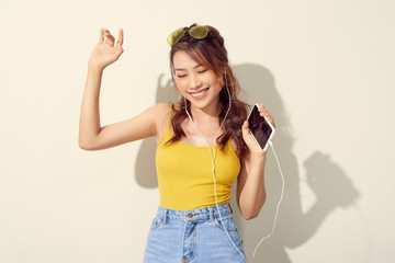 Asian woman listening and dancing to music on the white background