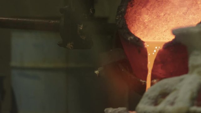 hot bronze being poured into molds in foundry