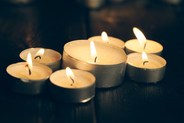 candles burning in darkness over black background. commemoration concept.