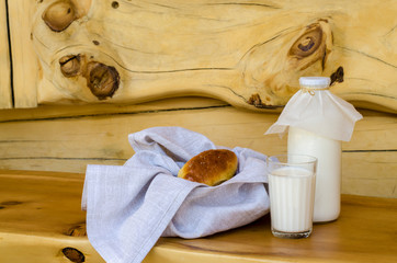 Fresh milk in a glass bottle and a glass, next to the pies on a wooden table. The concept of healthy organic products. Rusty style.
