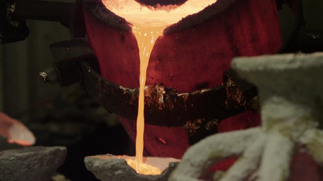 hot bronze being poured into molds in foundry
