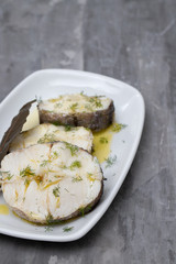 boiled fish with olive oil  and bay leaf in white dish