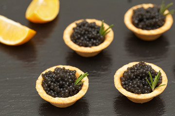 Tartlets with black caviar close up. Gourmet food close up, appetizer. Delicatessen. Gourmet food. Texture of caviar. Seafood. 