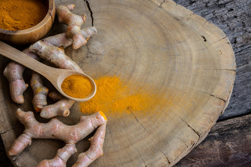 Stack of cut fresh turmeric on wood background, herb concept, traditional asian spice