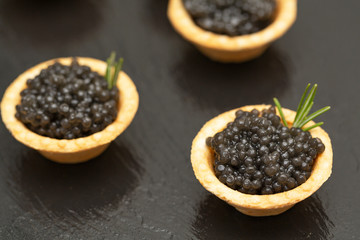 Tartlets with black caviar close up. Gourmet food close up, appetizer. Delicatessen. Gourmet food. Texture of caviar. Seafood. 