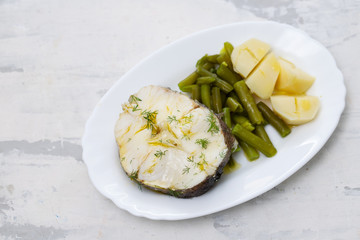 boiled fish with green beans and boiled potato on white dish