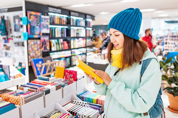 Young asian woman looking for a book in store