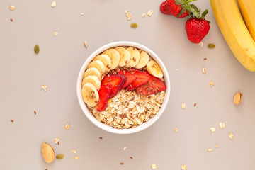 Smoothie bowl with muesli, strawberries, banana slices and flax seed. Healthy food concept. Flat...