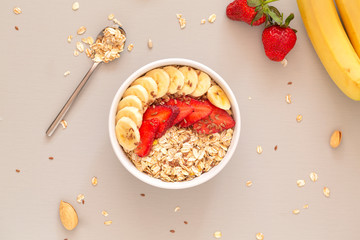 Smoothie bowl with muesli, strawberries, banana slices and flax seed. Healthy food concept. Flat...