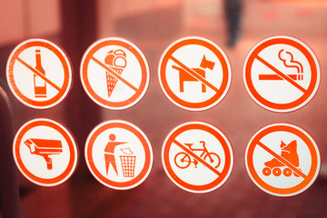 signs of prohibition of drinking alcohol, eating ice cream, dog walking, smoking, rollerblading and cycling on a glass surface; a sign to throw garbage in bins; video surveillance sign; yellow frames