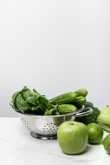 green apple near tasty vegetables and spinach leaves on white