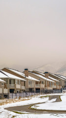 Fototapeta na wymiar Vertical Facade of homes viewed against snow capped mountain and white sky in winter