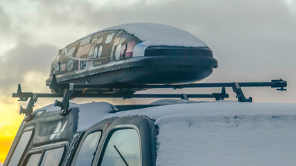 Panorama Black vehicle with a roof rack and rooftop cargo carrier viewed in winter