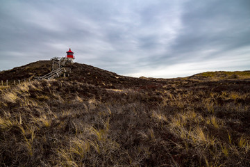 Red lighthouse on the hill in distance in Norddorf