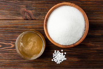 Honey and sugar on dark wooden background.