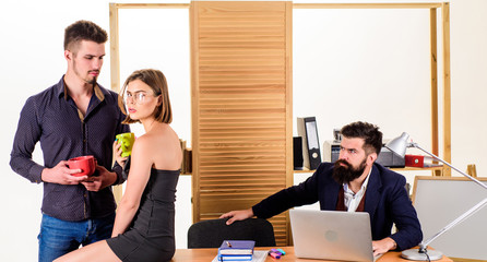 Satisfying desk lunch. Young colleagues talking during work lunch. Two coworkers having tea or coffee for lunch. Business partners talking on lunch break while angry colleague working in background