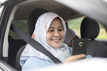 Muslim Lady Smiling When Looking at Her Phone in The Car