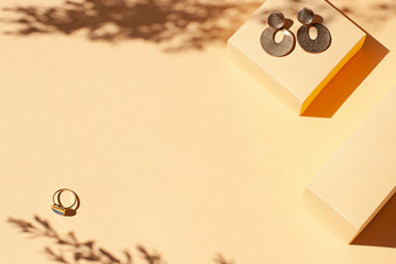 Fashion golden jewelry frame on the beige minimalistic background with harsh light. Top view. Copy space