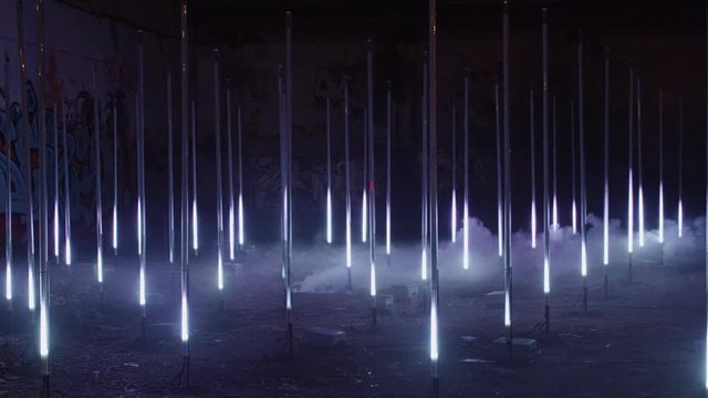 Creative and conceptual art installation of multiple led pillars or columns being lit up in synchronization in darkness with white light. Concept futuristic performance or artsy inspiration