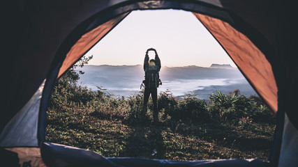 Happy hiker man standing at camping with backpack in morning on mountains.