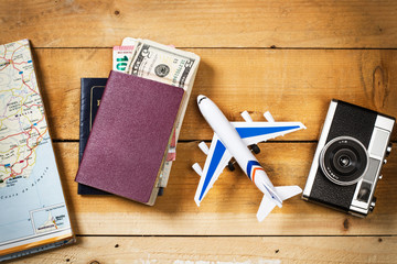 Preparación concepto de viaje, avión, dinero, pasaporte, mapa sobre mesa rústica de madera vista...