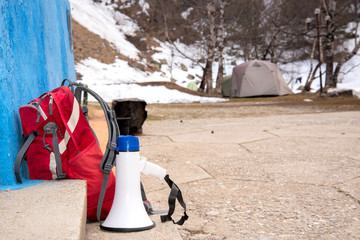 a red tourist backpack stands next to a megaphone loudspeaker on outdoor