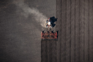 Top view of agricultural industrial tractor plows soil field for sowing , aerial shot from drone. Land cultivation, spring farming © DedMityay