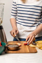 cropped view of woman holding knife near cutting board with strawberries on white