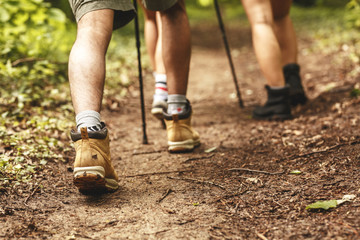 People hiking.Only legs and tracking boots are  visible. Rear view.