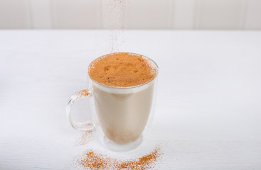 Glass cup of coffee latte with cinnamon on wooden table
