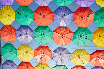 Fototapeta na wymiar Background of multicolored umbrellas hanging against the blue sky.