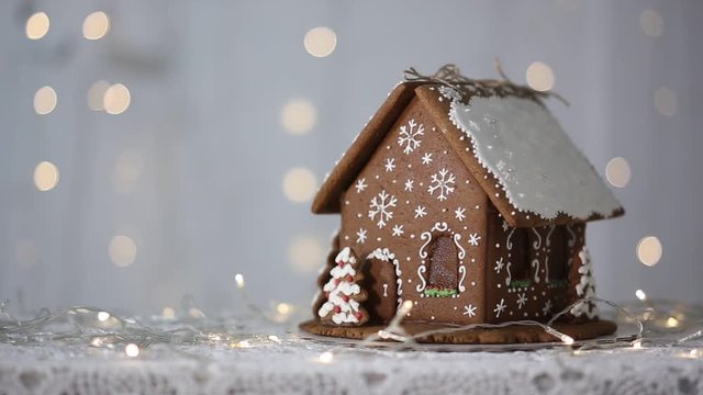 Handmade gingerbread house on the background of sparkling lights, decorated with snowflakes