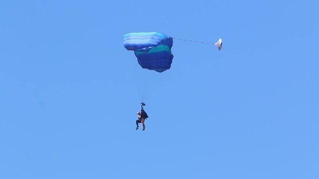 skydiver descends on a parachute wing type against a blue sky