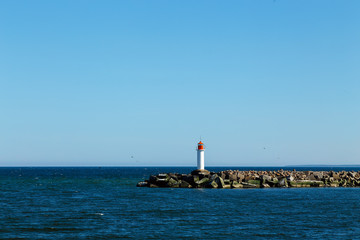 White lighthouse tower on blue sky background