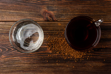 Cup of  coffee and water on dark wooden background.