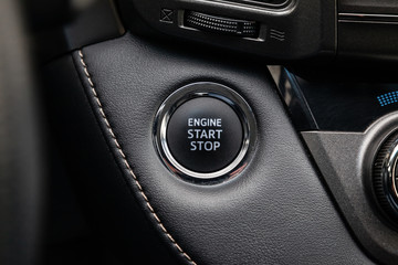 Button start and turn off the ignition of the car engine close-up on the dashboard, electric key, of modern design black and with elements chrome on the interior panel. Auto service industry.