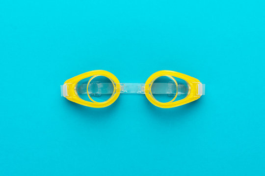 flat lay shot of yellow swimming goggles over turquoise blue background. minimalist photo of swimming goggles with central composition