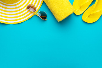 yellow beach accessories on turquoise blue background - sunglasses, towel. flip-flops and striped...