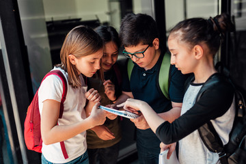 Group of classmates discussing about homework in front of school