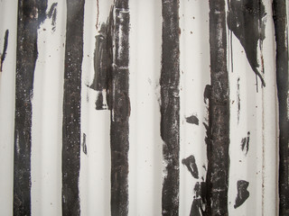 Background. Old metal wall with fins. Steel is visible close by. The interior surfaces are preserved white paint.