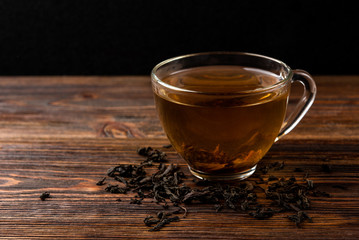 Cup of black tea on dark wooden background.