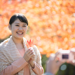 Obraz premium 紅葉を持ち微笑む女性